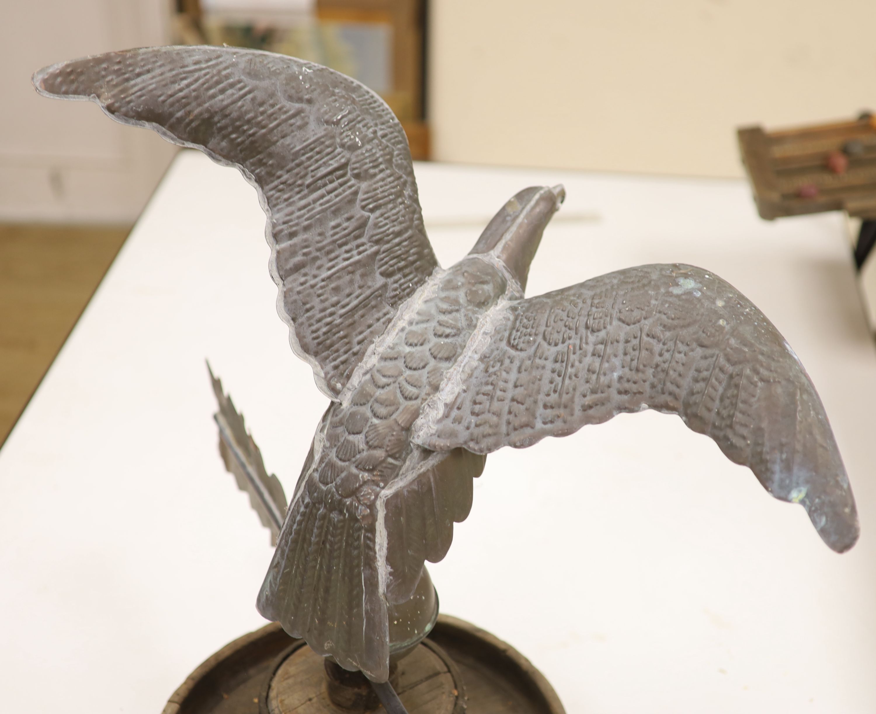 A 19th century American copper weather vane, modelled as an eagle, on an associated wooden base, width 62cm height 58cm